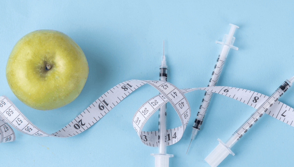 An apple with three syringes and a measuring tape
