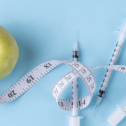 An apple with three syringes and a measuring tape